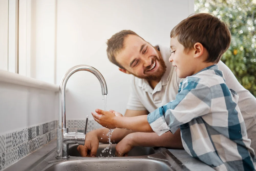 Vater und Sohn waschen sich die Hände am Küchenwasserhahn